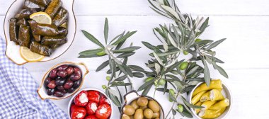 Geleneksel Yunan mutfağı. Üzüm yapraklarına sarılmış pirinç. Limonlu, baharatlı, çeşitli zeytinli ve acı biberli Dolma. Taze dallar ve ev yapımı yiyecekler..