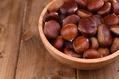 Tahta arka planda bir fincan kestane. Sonbahar hasadı ve olgun meyveler. Metin için boş alan.