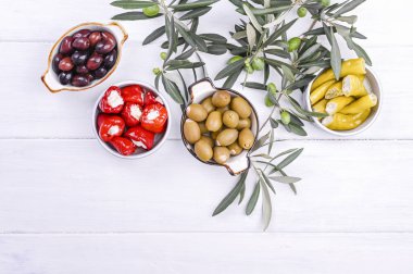 Geleneksel mezeler, Yunan mutfağından zeytinler. Beyaz ahşap arka plan. Yukarıdan bak. Taze zeytin dalları. Boşluğu kopyala.