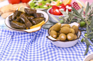 Geleneksel Yunan mutfağı. Üzüm yapraklarına sarılmış pirinç. Limonlu, baharatlı, çeşitli zeytinli ve acı biberli Dolma. Taze dallar ve ev yapımı yiyecekler..