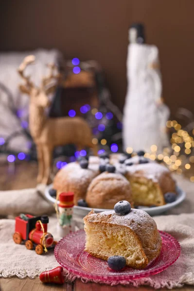 Weihnachtskuchen mit Beeren und Puderzucker auf einem hölzernen Hintergrund. Stück Kuchen. Traditionelles Gebäck in Italien. Bokeh im Hintergrund — Stockfoto