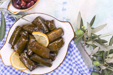 Geleneksel Yunan mutfağı. Üzüm yapraklarına sarılmış pirinç. Limonlu ve baharatlı Dolma. Ev yemeği. Zeytin dalları ve çeşitli baharatlı aperatifler.