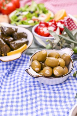 Geleneksel Yunan mutfağı. Üzüm yapraklarına sarılmış pirinç. Limonlu, baharatlı, çeşitli zeytinli ve acı biberli Dolma. Taze dallar ve ev yapımı yiyecekler..