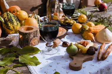 Sonbahar doğasında öğle yemeği için hazırlanmış bir masa, piknik. Hasat, sonbahar yemeği, şarap ve bardaklar. Açık hava toplantısı.
