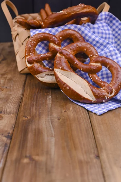 Bretzel bavarois orné d'un tissu bleu et blanc sur une planche en bois rustique - Munich Oktoberfest. Contexte et espace libre pour le texte. Cuire dans un panier. Pâtisseries traditionnelles pour le festival. — Photo