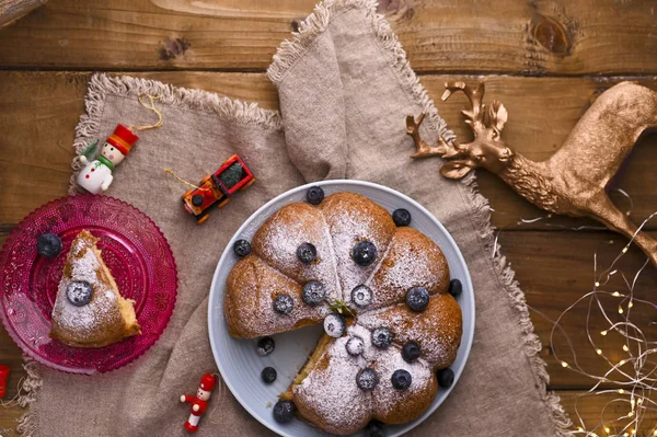 Weihnachtskuchen mit Beeren und Puderzucker auf einem hölzernen Hintergrund. Traditionelles Gebäck in Italien. — Stockfoto