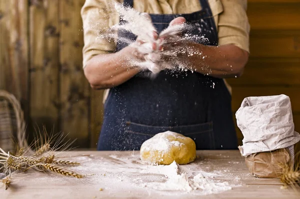Kvinnors händer, mjöl och dough.Levitation i en ram av deg och mjöl .En kvinna i ett förkläde förbereder deg för hembakning. Rustik stil foto. Träbord, veteöron och mjöl. Känslomässigt foto. — Stockfoto