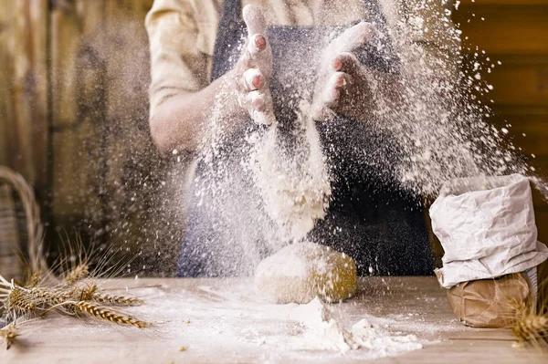 Women's hands, flour and dough.Levitation in a frame of dough and flour.A woman in an apron is preparing dough for home baking. Rustic style photo. Wooden table, wheat ears and flour. Emotional photo. — Stock Photo, Image