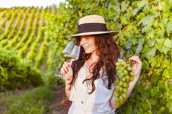 Ragazza con un bicchiere di vino e vigneti. Colline verdi con uva e i raggi del sole al tramonto. Stagione di vendemmia in Italia. — Foto Stock