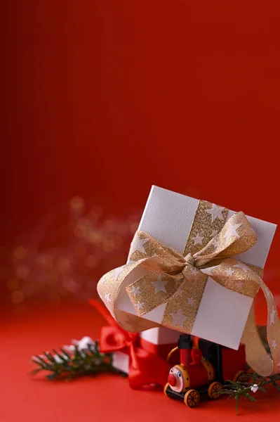 Fundo de Natal foco vermelho e seletivo. Caixas com presentes em um trem de madeira de brinquedo. Cartão de férias com espaço de cópia . — Fotografia de Stock