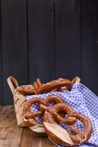 Bavorský preclík zdobený modrobílou látkou na rustikální dřevěné desce - Mnichov Oktoberfest. Pečeme v košíku. Pozadí a volné místo pro text. Tradiční pečivo pro festival — Stock fotografie