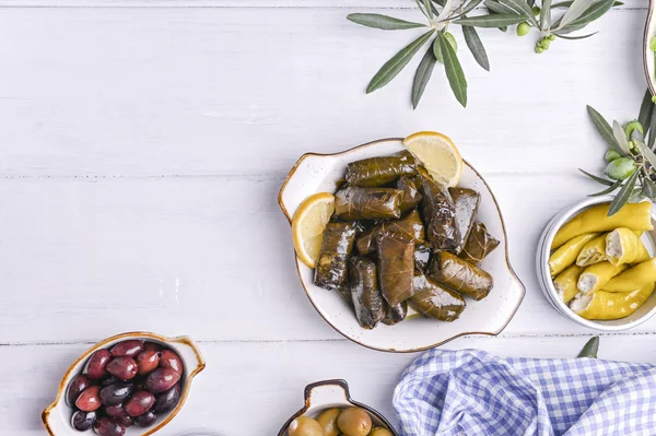 Geleneksel Yunan mutfağı. Üzüm yapraklarına sarılmış pirinç. Limonlu, baharatlı, çeşitli zeytinli ve acı biberli Dolma. Taze dallar ve ev yapımı yiyecekler..