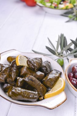 Geleneksel Yunan mutfağı. Üzüm yapraklarına sarılmış pirinç. Limonlu ve baharatlı Dolma. Ev yemeği. Zeytin dalları ve çeşitli baharatlı aperatifler.