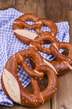 Bavyera krakeri, ahşap bir tahtanın üzerinde mavi ve beyaz bir bezle süslenmiş Münih Ekim Festivali. Dikey format. Metin için arkaplan ve boş alan. Festival için geleneksel hamur işleri.