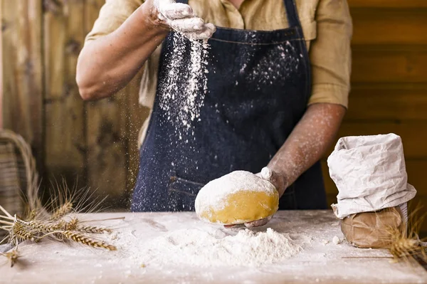 Kvinnors händer, mjöl och dough.Levitation i en ram av deg och mjöl .En kvinna i ett förkläde förbereder deg för hembakning. Rustik stil foto. Träbord, veteöron och mjöl. Känslomässigt foto. — Stockfoto