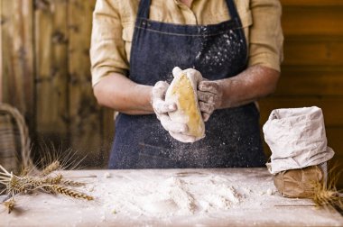 Kadın eli ve hamuru. Bir kadın ev yapımı için hamur hazırlıyor. Kırsal bir fotoğraf. Tahta masa, buğday kulakları ve un. Metin için boş alan.