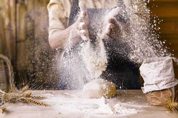 Womens hands, flour and dough.Levitation in a frame of dough and flour.A woman in an apron is preparing dough for home baking. Rustic style photo. Wooden table, wheat ears and flour. Emotional photo. — Stock Photo, Image