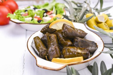 Geleneksel Yunan mutfağı. Üzüm yapraklarına sarılmış pirinç. Limonlu, baharatlı ve Yunan salatalı Dolma. Ev yemeği. Zeytin dalları ve çeşitli baharatlı aperatifler.