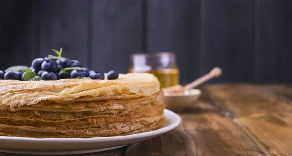 Pancake dengan blueberry dan madu di piring, di atap kayu. Pastri tradisional untuk festival Rusia Maslenitsa. ruang kosong untuk teks. Tembakan jarak dekat . — Stok Foto
