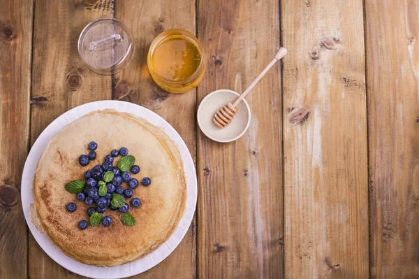 Pancake dengan blueberry dan madu di piring, di atap kayu. Pastri tradisional untuk festival Rusia Maslenitsa. ruang kosong untuk teks. Di atas. Banner — Stok Foto