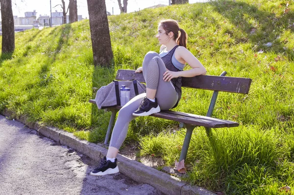 Sportowa kobieta odpoczywa po ciężkim treningu w górach o zachodzie słońca. Sportowe ciuchy. Aktywny tryb życia. — Zdjęcie stockowe