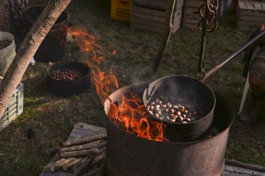 Sokakta kestane satıp kızartıyorlar. İtalya 'da yemek fuarı. Bir adam büyük bir tencereyi ateşe veriyor. Boşluğu kopyala 