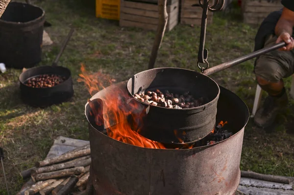 Verkauf und Rösten von Kastanien auf der Straße. Food Fair in Italien. Große Pfanne in Flammen. Kopierraum — Stockfoto