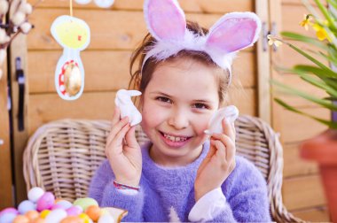 Paskalya. Renkli yumurtaları ve çikolata renkli yumurtaları olan küçük bir kız. Evde Paskalya tatilin kutlu olsun. Dekor ve dekorasyon masanın üstünde. Boşluğu kopyala.