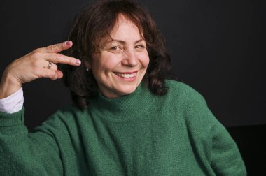 Kadın yaş modeli. Eğlence ve başarı duyguları, jest ve el işareti gösteriyor. Siyah arka plandaki kadın. Metin için boş alan. Boşluğu kopyala