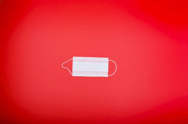 Coronavirus. Yeni Covid 2019 ve 2020 salgını. Büyük kırmızı arka planda virüslere karşı koruyucu bir maske. Üst Manzara. Metin için boş alan. Uzayı kopyala Düz yatıyordu