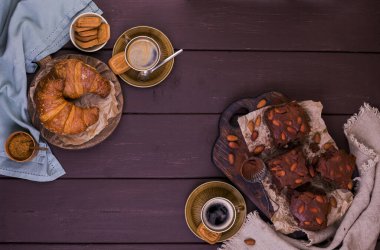 Brownie, tahtadan yapılmış bademli çikolatalı kekler ve kakao serpilmiş kruvasan. Ev yapımı kekler. Üst Manzara. Metin için boş alan.