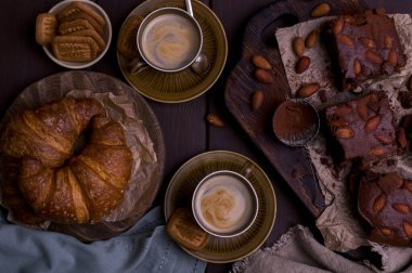 Kahvaltıda Brownie ve kruvasan ve aromatik kahve. Geleneksel Amerikan turtası ve İtalyan espresso. Lezzetli bir klasik kahvaltı. Üst Manzara. Metin için boş alan. Kruvasan Üst Görünümü. 