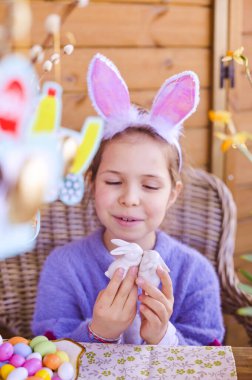 Paskalya. Renkli yumurtaları ve çikolata renkli yumurtaları olan küçük bir kız. Evde Paskalya tatilin kutlu olsun. Kız eğleniyor.
