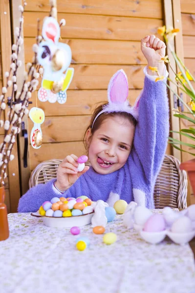Пасха. Маленькая девочка с цветными яйцами в руках и шоколадными яйцами. С праздником Пасхи дома. Декор и украшения на столе. Принято. С праздником! — стоковое фото
