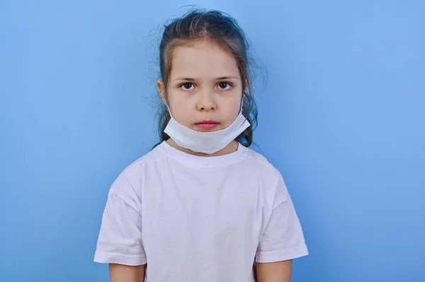 Baby im Coronavirus. Weltpandemiekonzept COVID 19. Kleines Mädchen in medizinischer Schutzmaske zeigt traurige Gefühle. Kopierraum und Blu-Hintergrund — Stockfoto