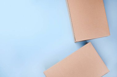 İşaretlenmemiş karton paket kutusu, mavi arka planda fırçalanarak strese sokuldu. Teslimat konsepti, posta, varış yerleri, karantina süresi konuyla ilgili. Uzayı kopyala Yukarıda..