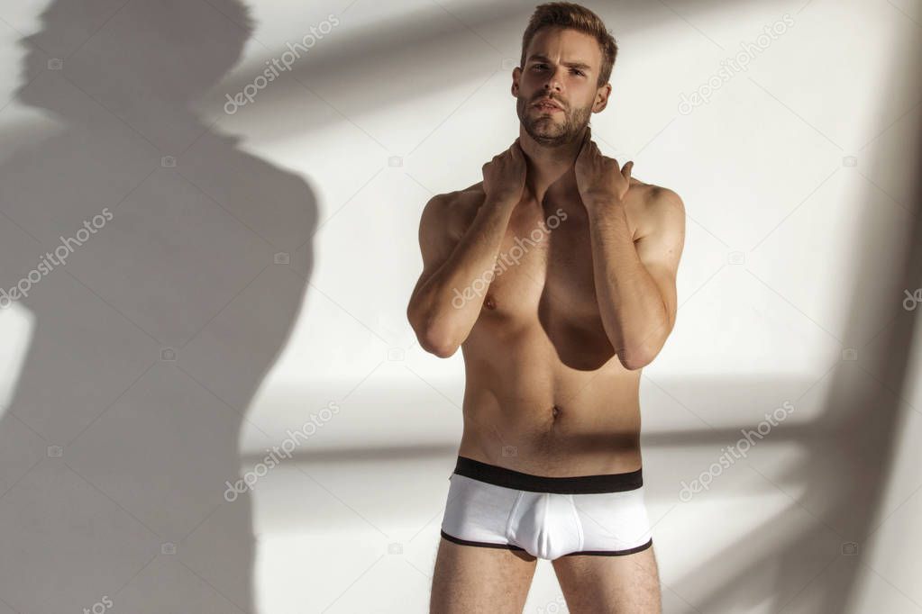 Handsome sport sexy stripped guy portrait with white underwear on isolated white background and shadows