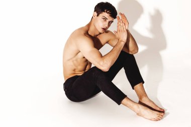 Kas gücü, beyaz izole yazı tipi arka planında kot pantolonlu, güzel, soyulmuş erkek model.