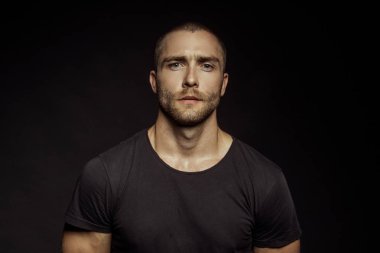 Siyah yalıtılmış yazı tipi arka planında kot kotlu siyah tişörtlü, kaslı, güzel, soyulmuş erkek model.