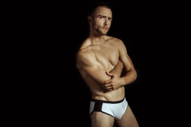 Siyah izole font arka planda beyaz iç çamaşırlı güçlü kaslı erkek model.