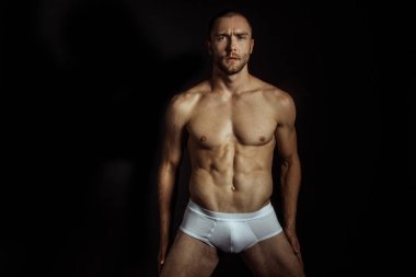 Siyah izole font arka planda beyaz iç çamaşırlı güçlü kaslı erkek model.