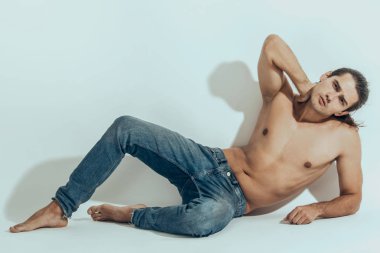 Kas gücü, beyaz izole yazı tipi arka planında kot pantolonlu, güzel, soyulmuş erkek model.