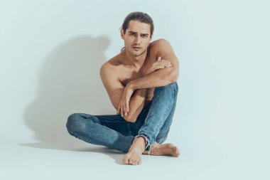 Kas gücü, beyaz izole yazı tipi arka planında kot pantolonlu, güzel, soyulmuş erkek model.