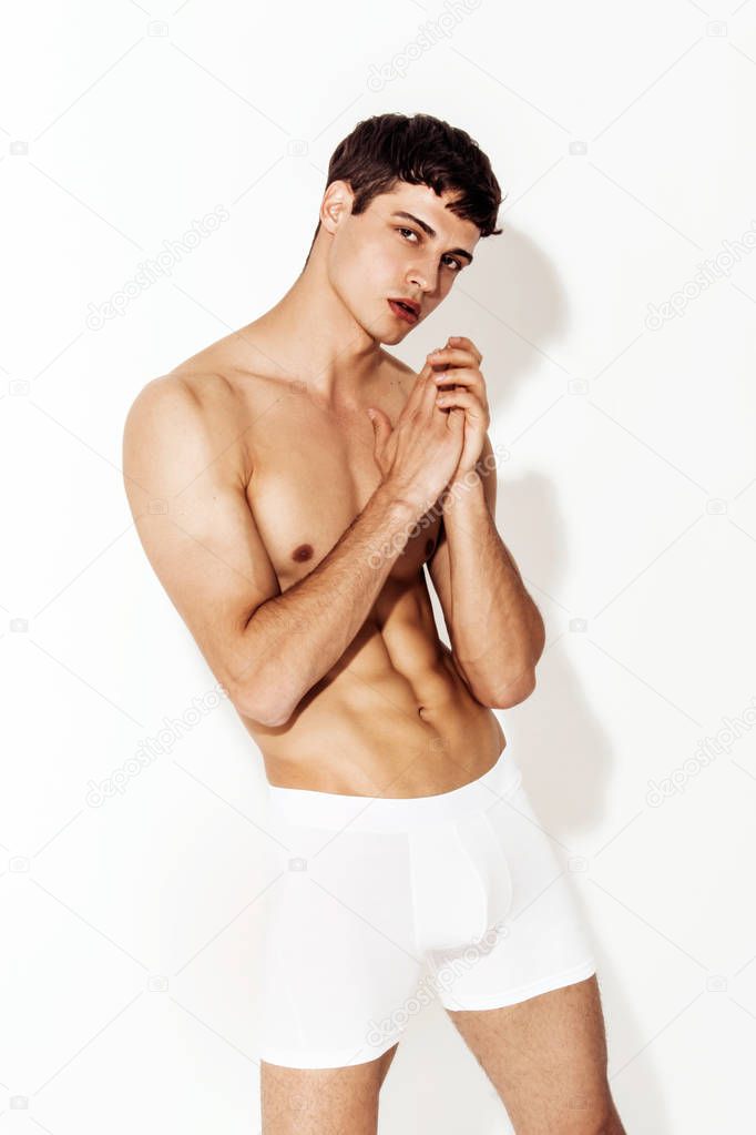 Strong stripped muscle male model in white underwear boxers on white isolated font background