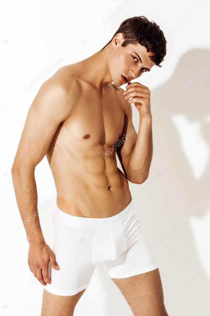 Strong stripped muscle male model in white underwear boxers on white isolated font background