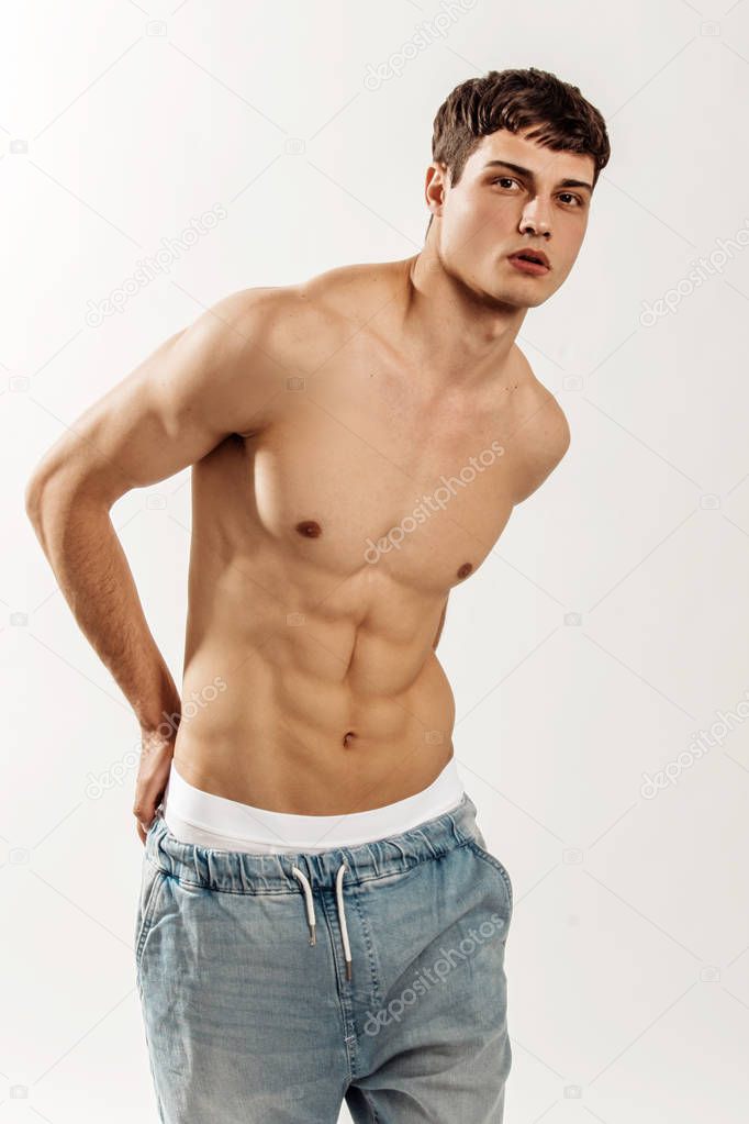 Muscle strong beautiful stripped male model in denim jeans on white isolated font background with shadow