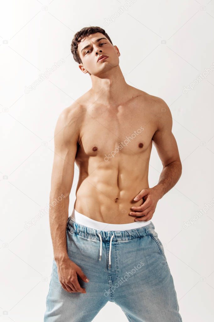 Muscle strong beautiful stripped male model in denim jeans on white isolated font background with shadow