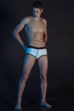 Yakışıklı seksi erkek portresi, beyaz iç çamaşırlı, izole siyah arka planda, renkli ışıklı.