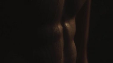İzole edilmiş siyah arka planda dumanlı, su damlalarının içindeki seksi sporcu.