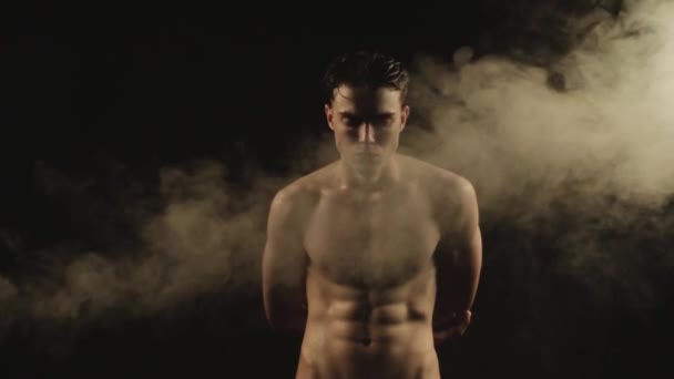 Sexy deporte despojado chico en agua gotas con humo en aislado negro fondo — Vídeo de stock